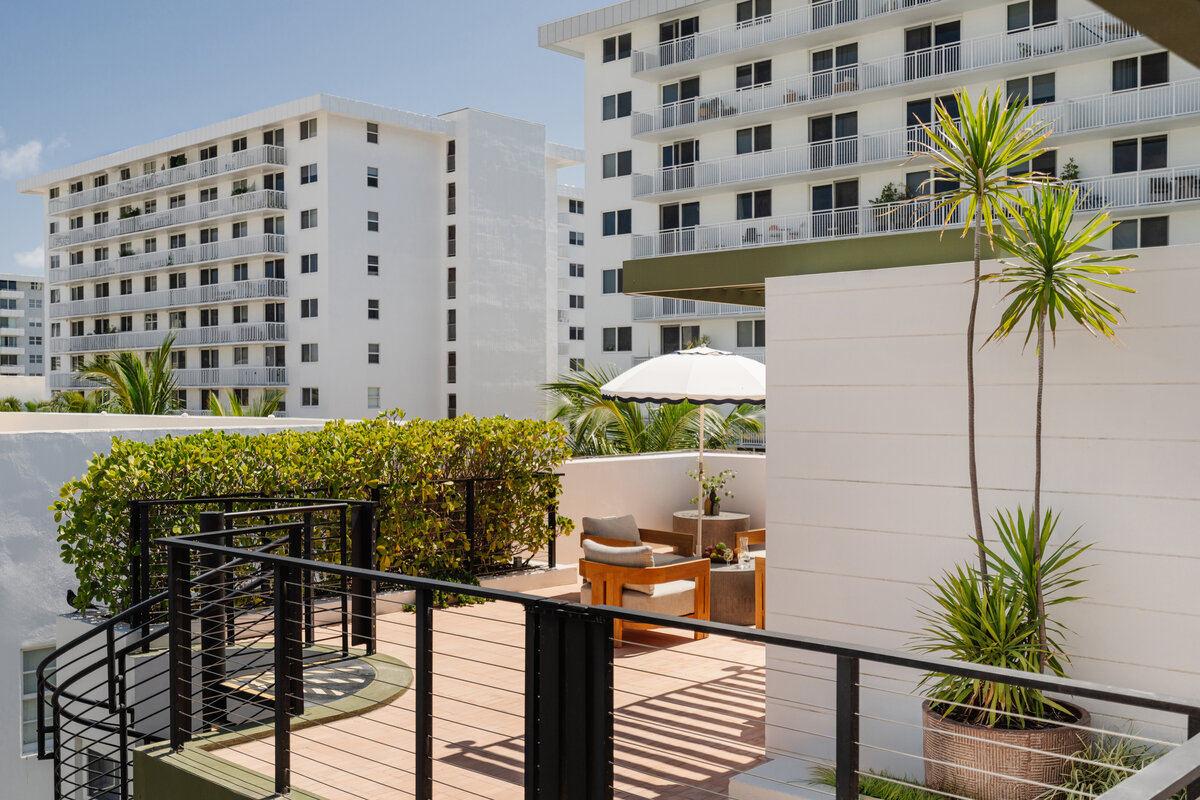 A balcony with a wooden deck, black railing, and outdoor furniture
